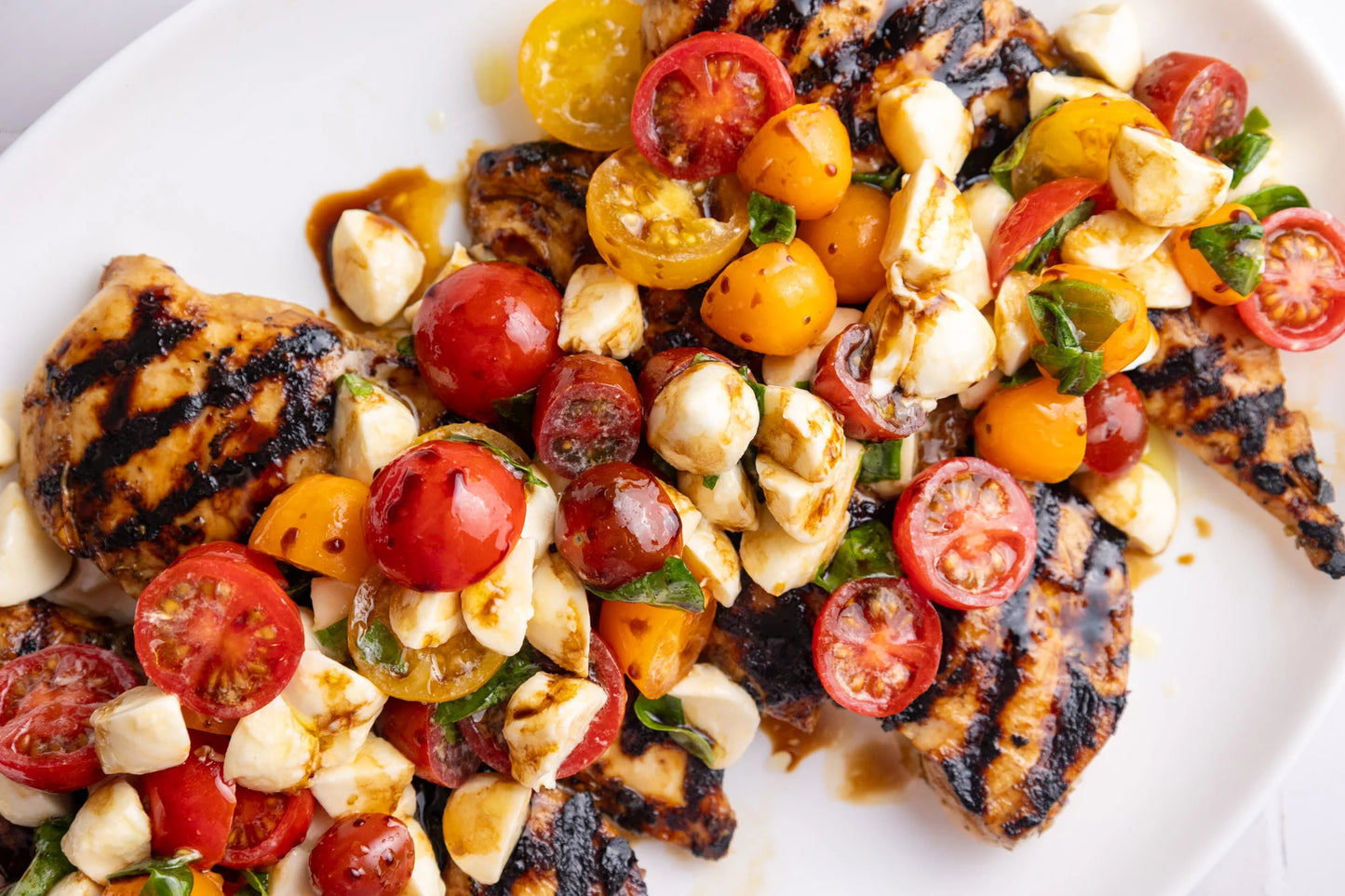 Poulet grillé sur riz beurre à l’ail & salade caprese bocconcini, tomates réduction balsamique
